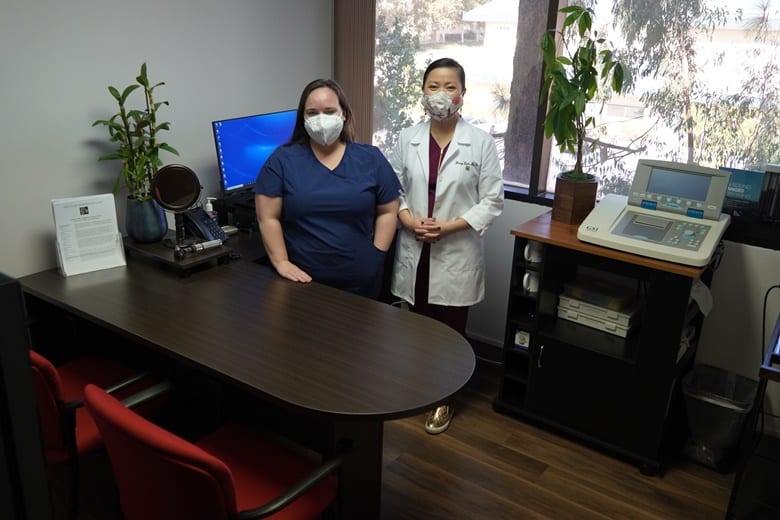 two team members standing by desk wearing masks